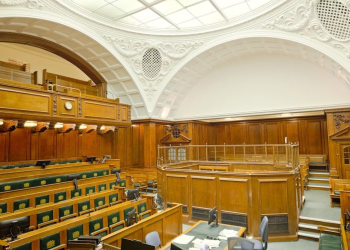 Vista interior de una sala de audiencias histórica en Londres con un diseño ornamentado y muebles de madera.